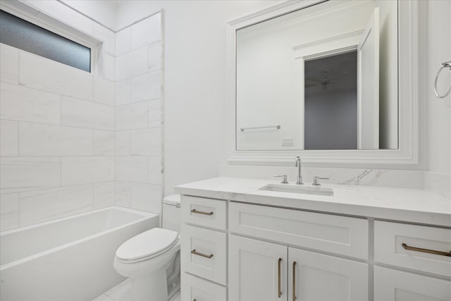 full bathroom with ceiling fan, tiled shower / bath, vanity, and toilet