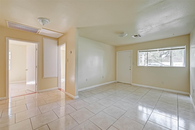 empty room with a textured ceiling and light tile patterned floors