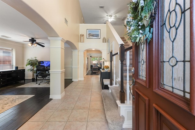 entryway with ceiling fan, light tile patterned floors, ornamental molding, and decorative columns