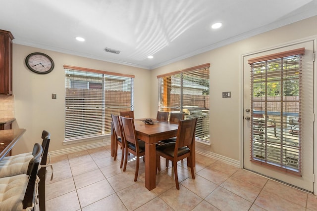 tiled dining area with a healthy amount of sunlight and crown molding