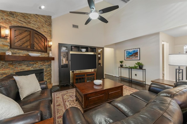 living room featuring ceiling fan, ornamental molding, high vaulted ceiling, dark hardwood / wood-style flooring, and a stone fireplace