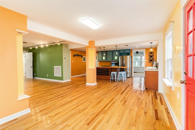 kitchen with hardwood / wood-style floors, track lighting, decorative light fixtures, sink, and stainless steel fridge