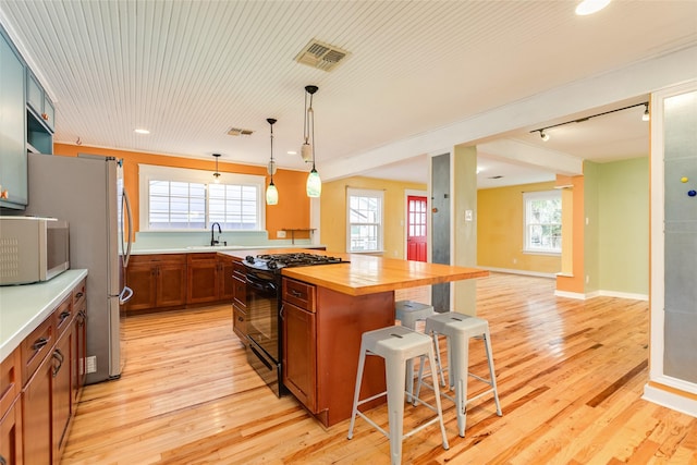 kitchen featuring a kitchen bar, black gas range oven, a kitchen island, pendant lighting, and butcher block countertops