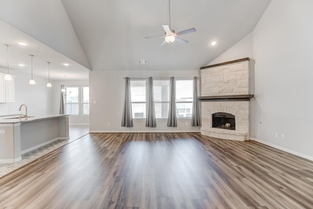 unfurnished living room featuring hardwood / wood-style floors, a fireplace, ceiling fan, and sink