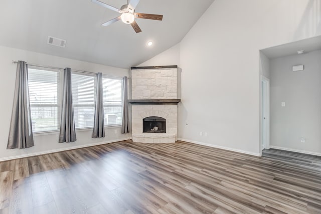 unfurnished living room featuring ceiling fan, a stone fireplace, hardwood / wood-style floors, and a wealth of natural light