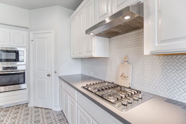 kitchen with stainless steel appliances, light tile patterned floors, white cabinetry, and tasteful backsplash