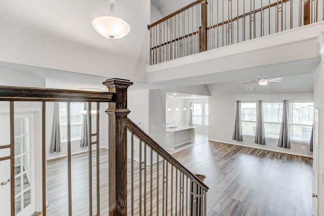 stairs featuring ceiling fan, hardwood / wood-style floors, a towering ceiling, and plenty of natural light