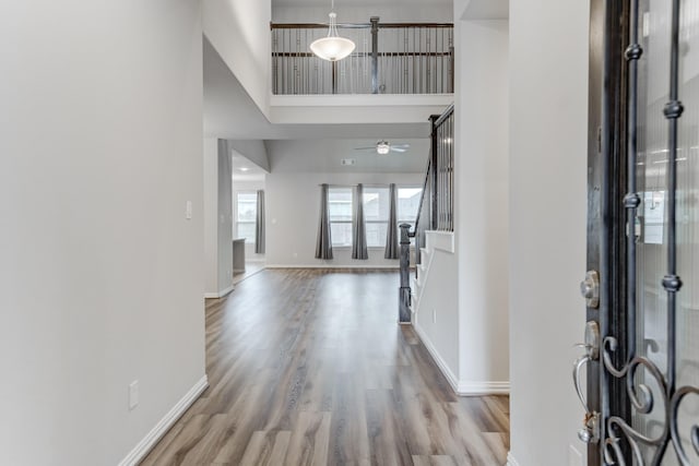 foyer entrance featuring a high ceiling, ceiling fan, and light wood-type flooring