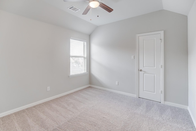 carpeted spare room with ceiling fan and vaulted ceiling