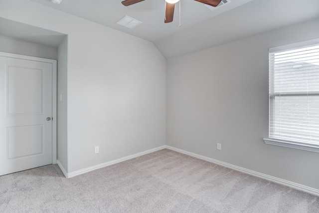 spare room featuring ceiling fan, light carpet, and vaulted ceiling