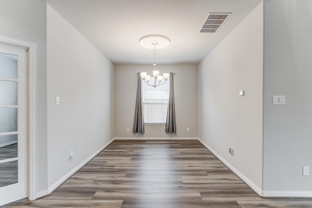 spare room featuring a chandelier and hardwood / wood-style floors