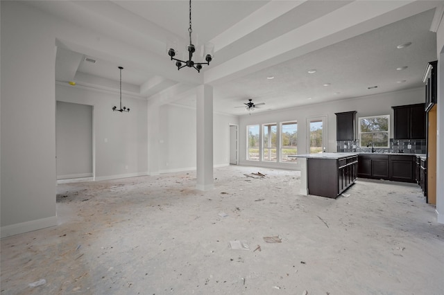 unfurnished living room featuring a raised ceiling and ceiling fan with notable chandelier