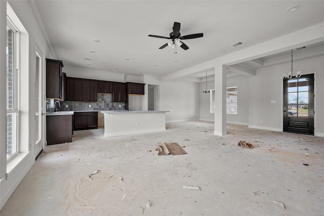 unfurnished living room featuring ceiling fan with notable chandelier, ornamental molding, and sink