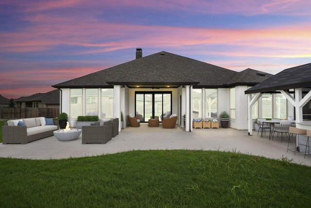 back house at dusk featuring a yard, an outdoor living space, and a patio