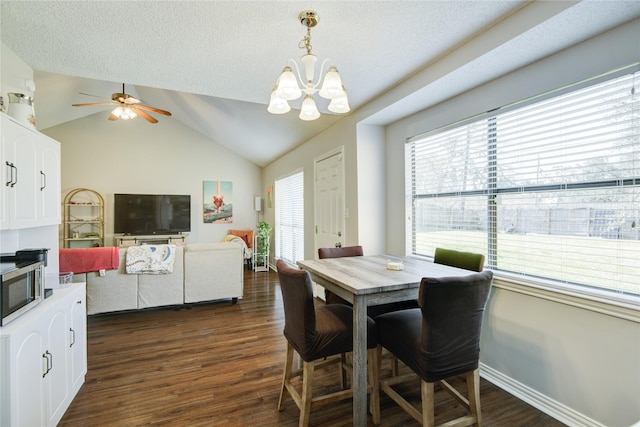 dining space featuring ceiling fan with notable chandelier, a textured ceiling, lofted ceiling, and dark hardwood / wood-style floors