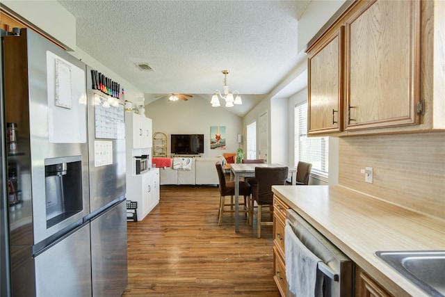 kitchen featuring decorative light fixtures, vaulted ceiling, tasteful backsplash, dark hardwood / wood-style floors, and appliances with stainless steel finishes