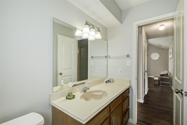 bathroom featuring a textured ceiling, hardwood / wood-style floors, vanity, and toilet