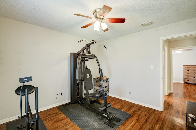 exercise area featuring a textured ceiling, ceiling fan, and dark wood-type flooring