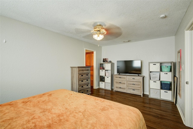 bedroom with ceiling fan, a textured ceiling, and dark hardwood / wood-style floors