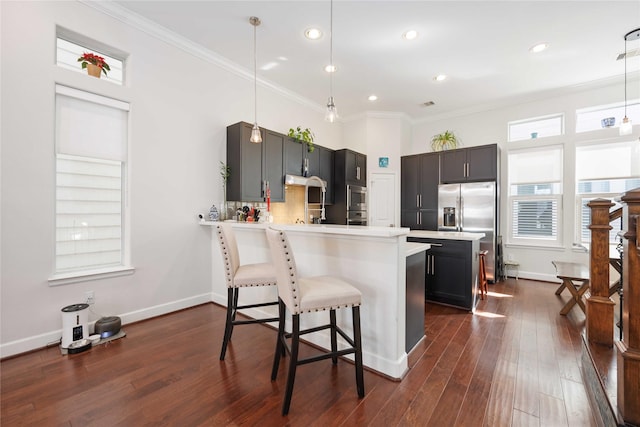 kitchen featuring ornamental molding, a peninsula, light countertops, a kitchen bar, and pendant lighting