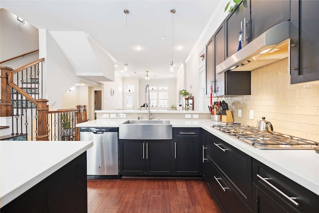 kitchen featuring stainless steel appliances, light countertops, hanging light fixtures, a sink, and under cabinet range hood