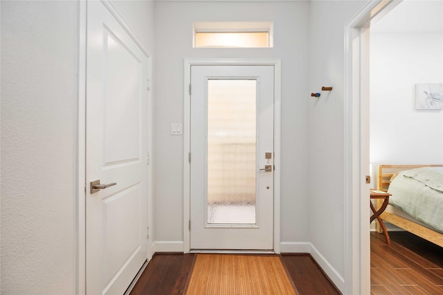 doorway to outside featuring baseboards and wood finished floors