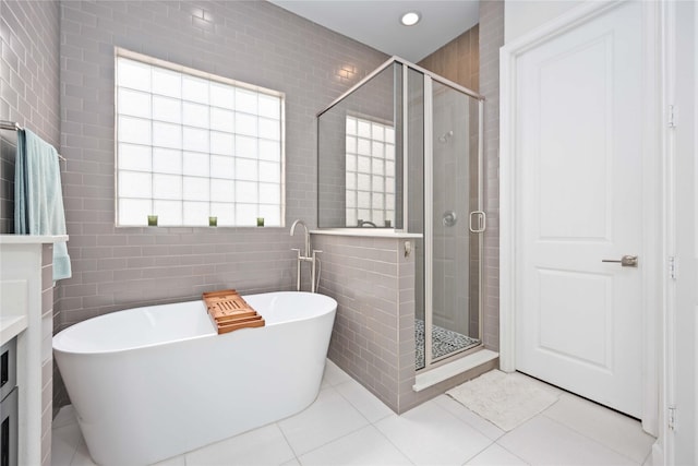 bathroom with a soaking tub, tile patterned floors, a shower stall, tile walls, and recessed lighting