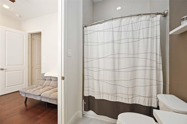 bathroom featuring curtained shower, toilet, and wood finished floors