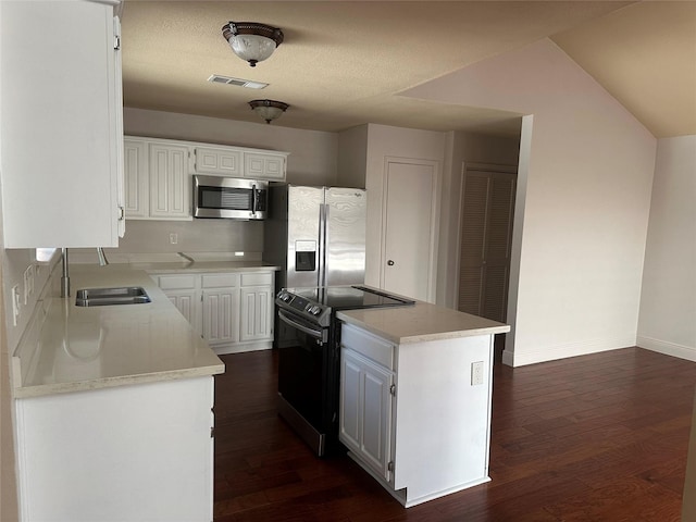 kitchen with dark wood finished floors, white cabinets, a kitchen island, and stainless steel appliances