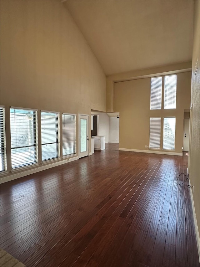 unfurnished living room with high vaulted ceiling, a healthy amount of sunlight, and dark wood finished floors