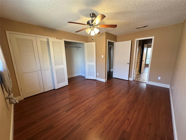 unfurnished bedroom with visible vents, ceiling fan, baseboards, dark wood finished floors, and a textured ceiling