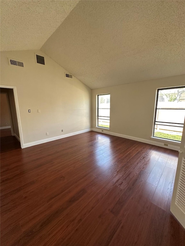 unfurnished room featuring visible vents, lofted ceiling, and dark wood finished floors