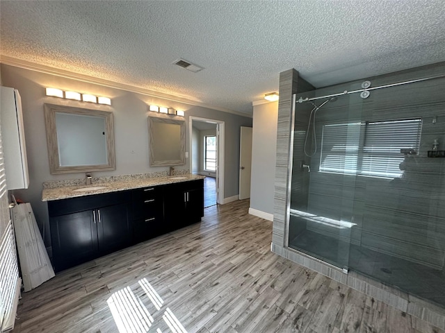 full bathroom featuring a shower stall, wood finished floors, visible vents, and a sink