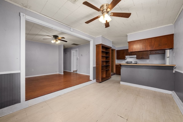 kitchen with ornamental molding, ceiling fan, stainless steel range oven, and kitchen peninsula