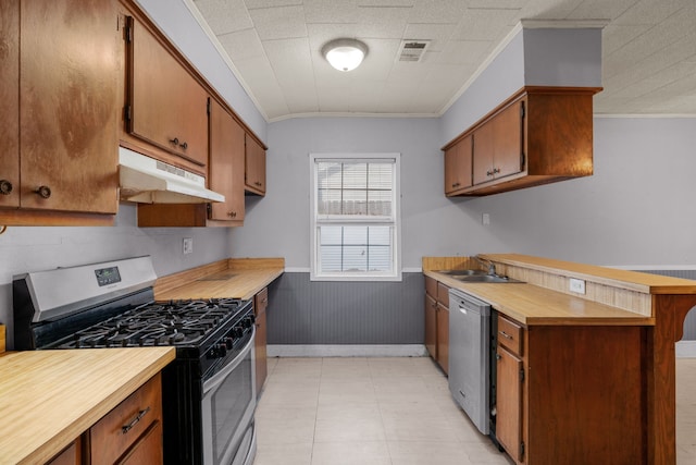 kitchen with wood walls, appliances with stainless steel finishes, crown molding, and sink