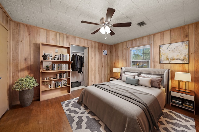 bedroom with dark wood-type flooring, a closet, ceiling fan, and a spacious closet