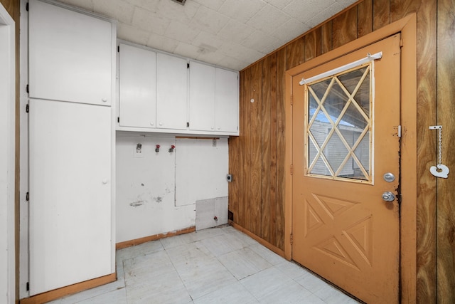 clothes washing area featuring wood walls and cabinets