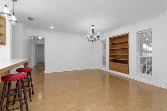 dining area with built in shelves, light wood-type flooring, ornamental molding, and a chandelier