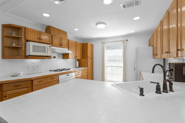 kitchen with white appliances, ornamental molding, tile countertops, decorative backsplash, and sink