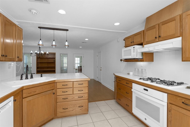 kitchen featuring white appliances, crown molding, kitchen peninsula, sink, and backsplash