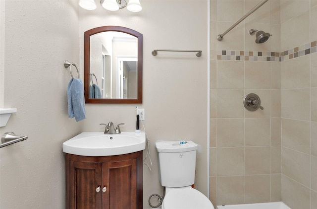 bathroom with tiled shower, vanity, and toilet