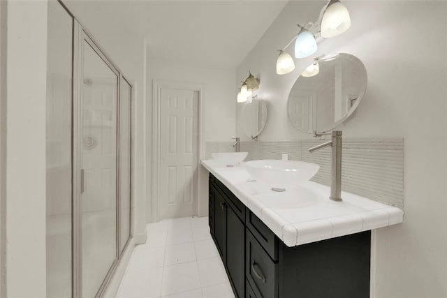 bathroom with tasteful backsplash, tile patterned flooring, walk in shower, and vanity