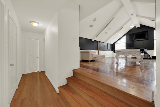 interior space with light hardwood / wood-style floors and vaulted ceiling with beams