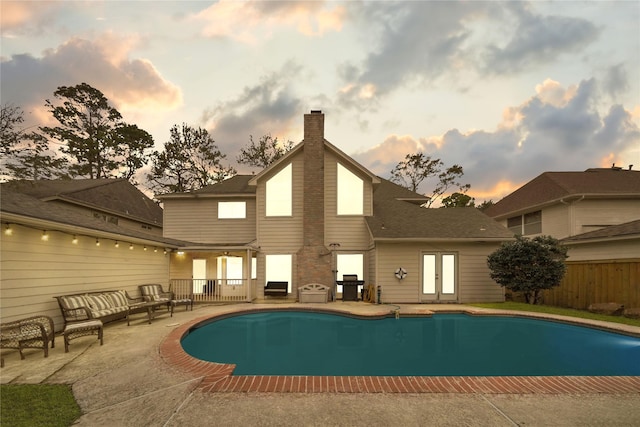 pool at dusk featuring area for grilling and a patio area