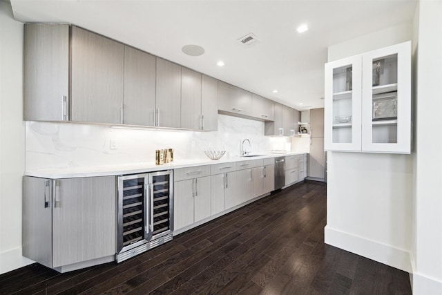 kitchen featuring dark wood-type flooring, wine cooler, backsplash, and gray cabinetry