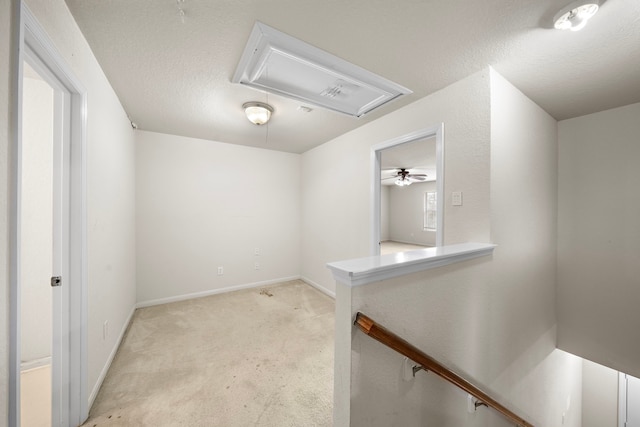 spare room featuring a textured ceiling, ceiling fan, and light colored carpet