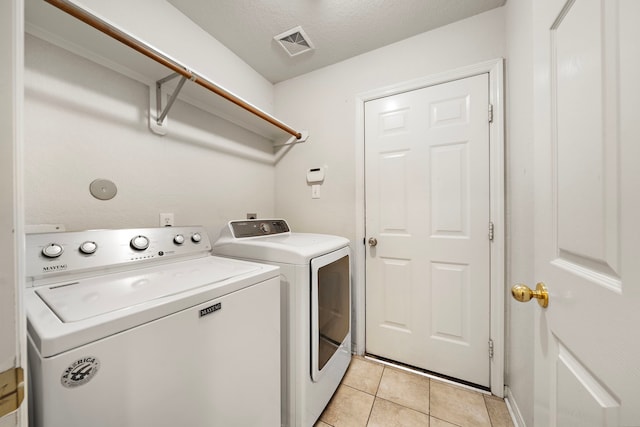 washroom featuring a textured ceiling, light tile patterned floors, and independent washer and dryer