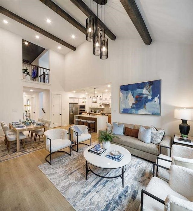 living room featuring light wood-type flooring, a towering ceiling, and beamed ceiling