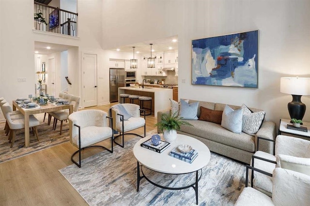 living room featuring sink, a towering ceiling, and light wood-type flooring