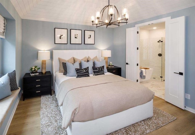 bedroom with ensuite bath, a chandelier, and wood-type flooring